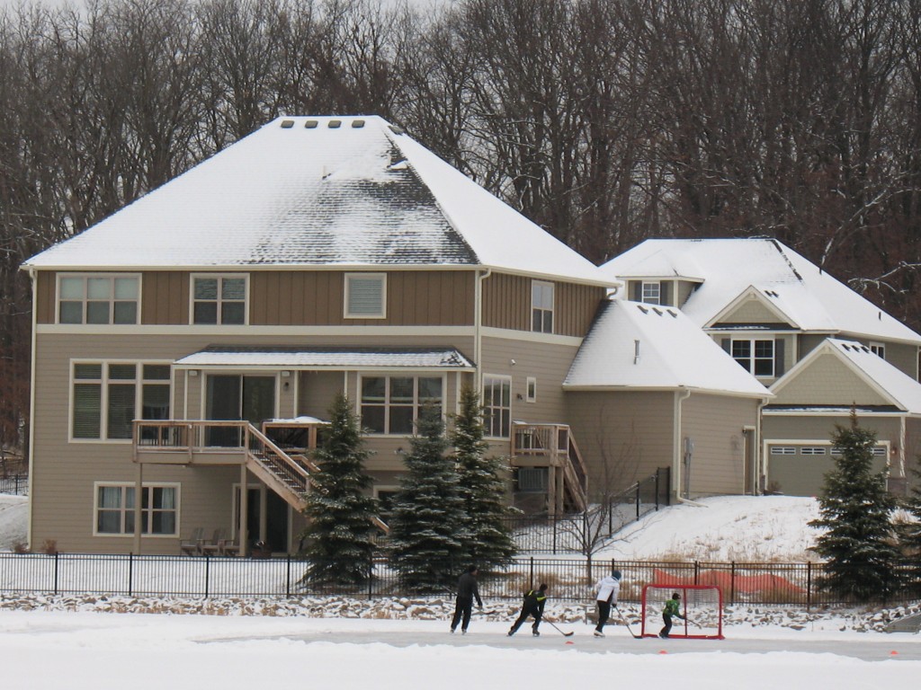 pond hockey at Spring Meadows of Plymouth, family playing ice hockey in their backyard, pond hockey in the suburbs, luxury homes have hockey rink in their backyard, luxury homes of Spring Meadows with ice skating rink in the backyard. 